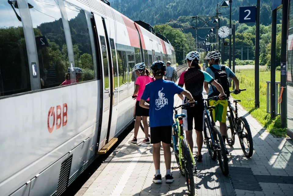 Radfahrer mit ihren Fahrrädern am Bahnsteig neben einem ÖBB-Zug